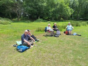 A group of birders taking a rest sitting on the grass.